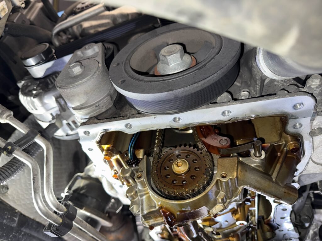 Lower front engine and chain-drive components exposed during oil pump repair on a Jeep Grand Cherokee.
