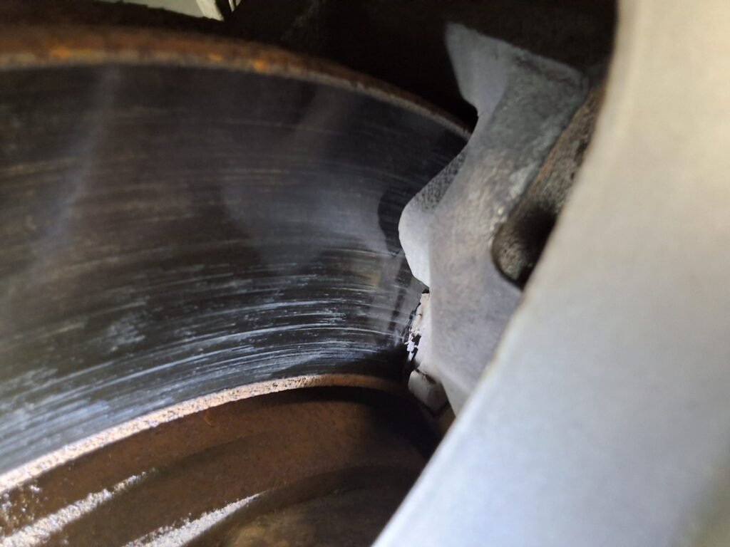 Close-up of worn front brake components on a Chrysler Town & Country during inspection.