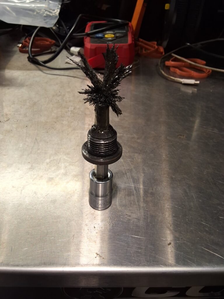 Heavy metallic debris collected on the magnetic rear differential drain plug from a Nissan Xterra.